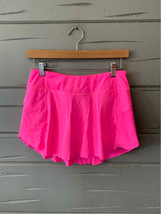Bright pink athletic skort with built-in shorts and a wide waistband hanging on wooden hanger.