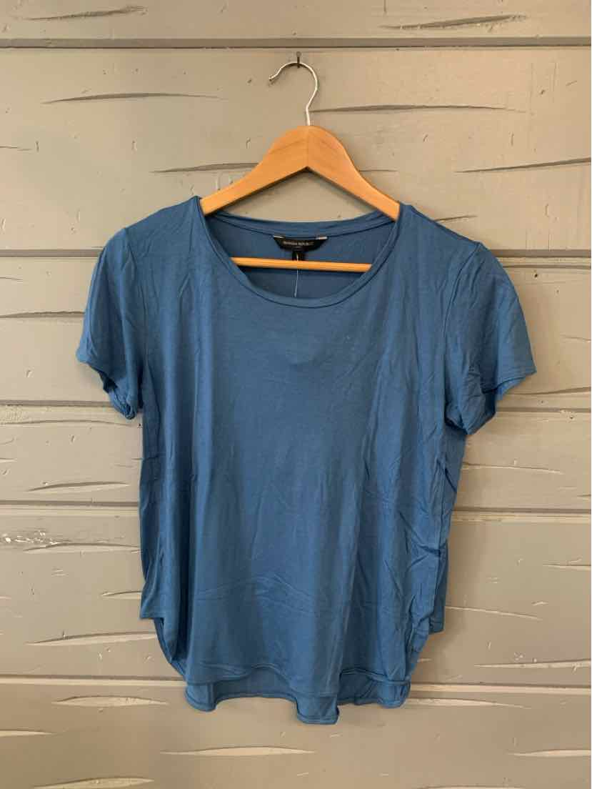 Blue short-sleeve scoop neck women's t-shirt on wooden hanger against gray wooden wall.