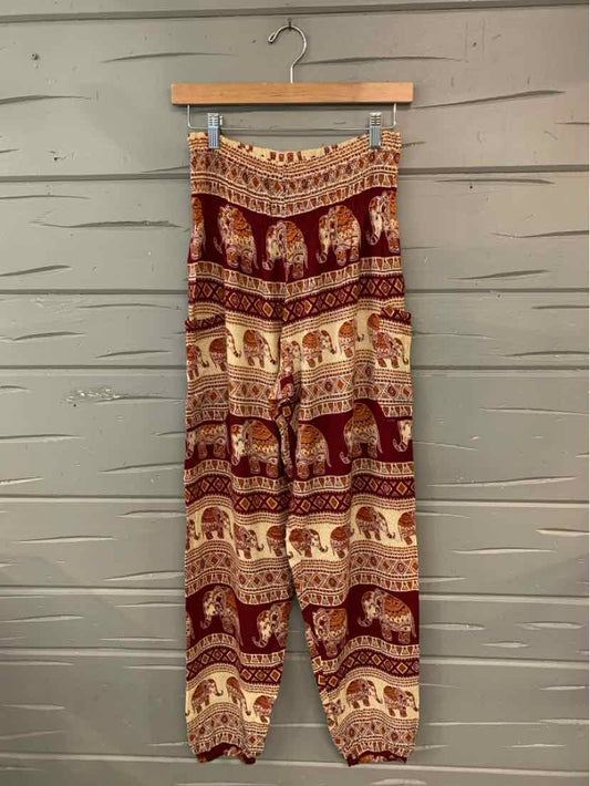 Red elephant-print pants with gathered cuffs and an elastic waistband hanging on a wooden hanger.
