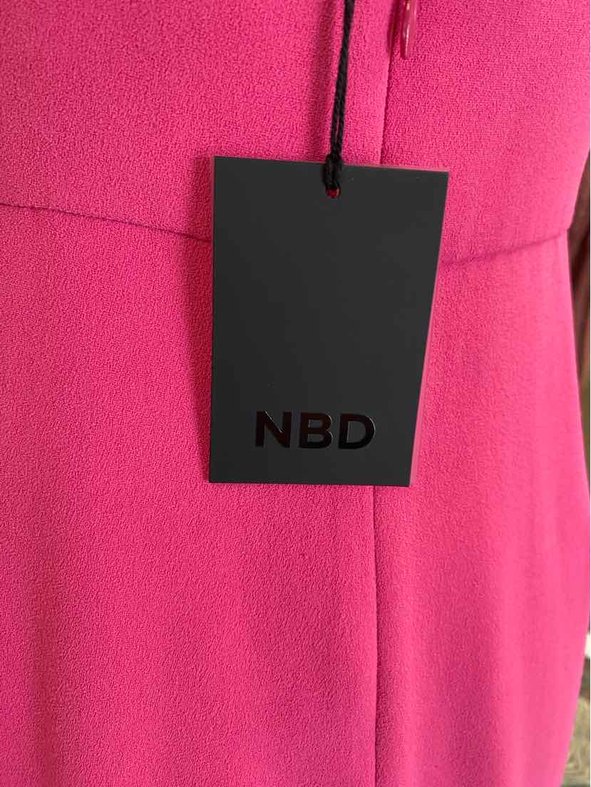 Bright pink fabric with stitched seam detail and a black rectangular tag labeled NBD hanging from a matching pink string.