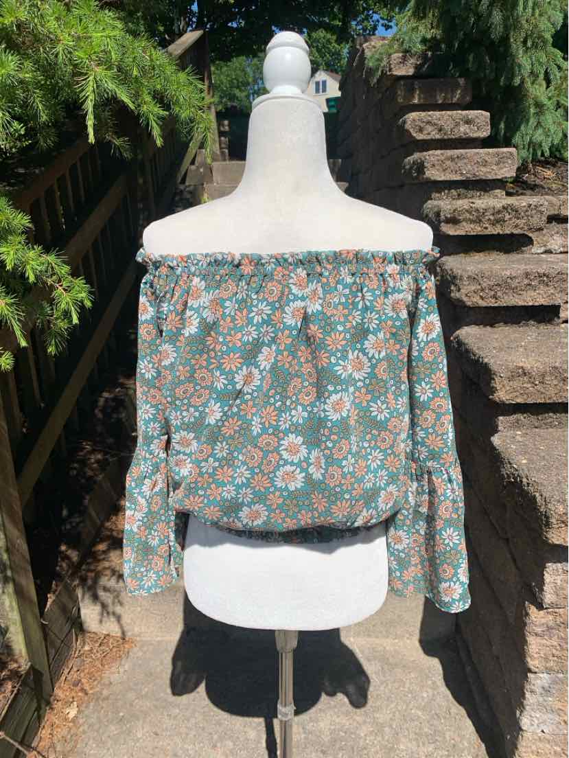 Off-shoulder long-sleeve blouse with green base and pink lily floral print, loose fit.