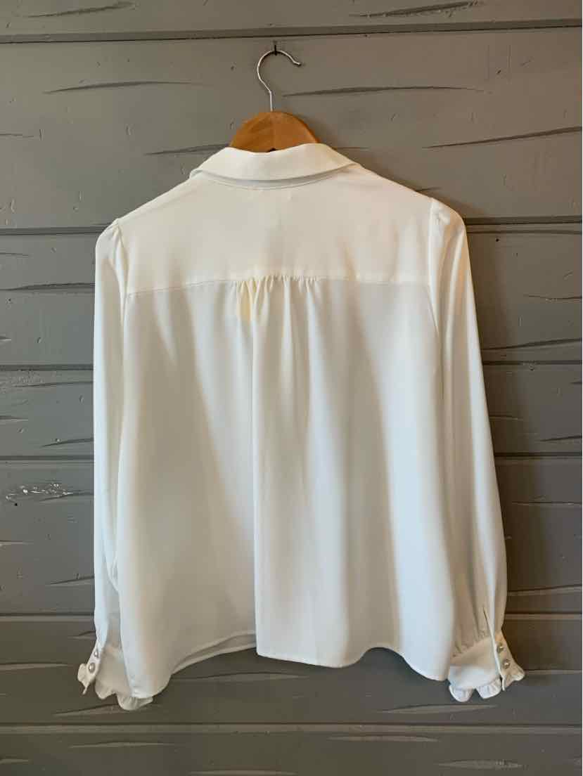 White long-sleeve blouse with a classic collar, buttoned cuffs, and gathered back yoke detail.