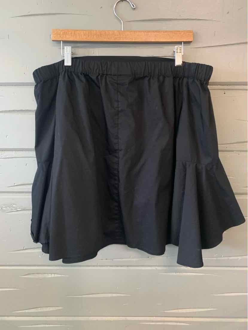 Black flared skirt with elastic waistband and layered hem detail hanging on wooden hanger.