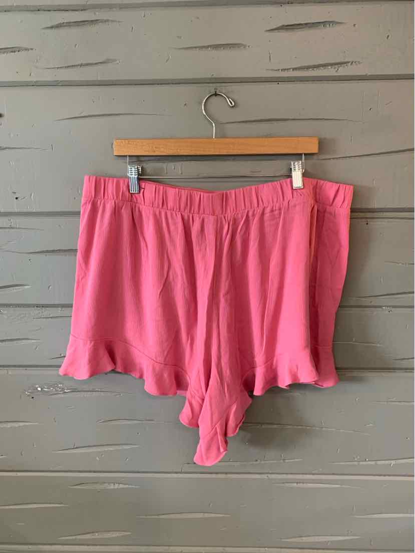 Pink soft fabric shorts with elastic waistband and relaxed fit hanging on wooden hanger.