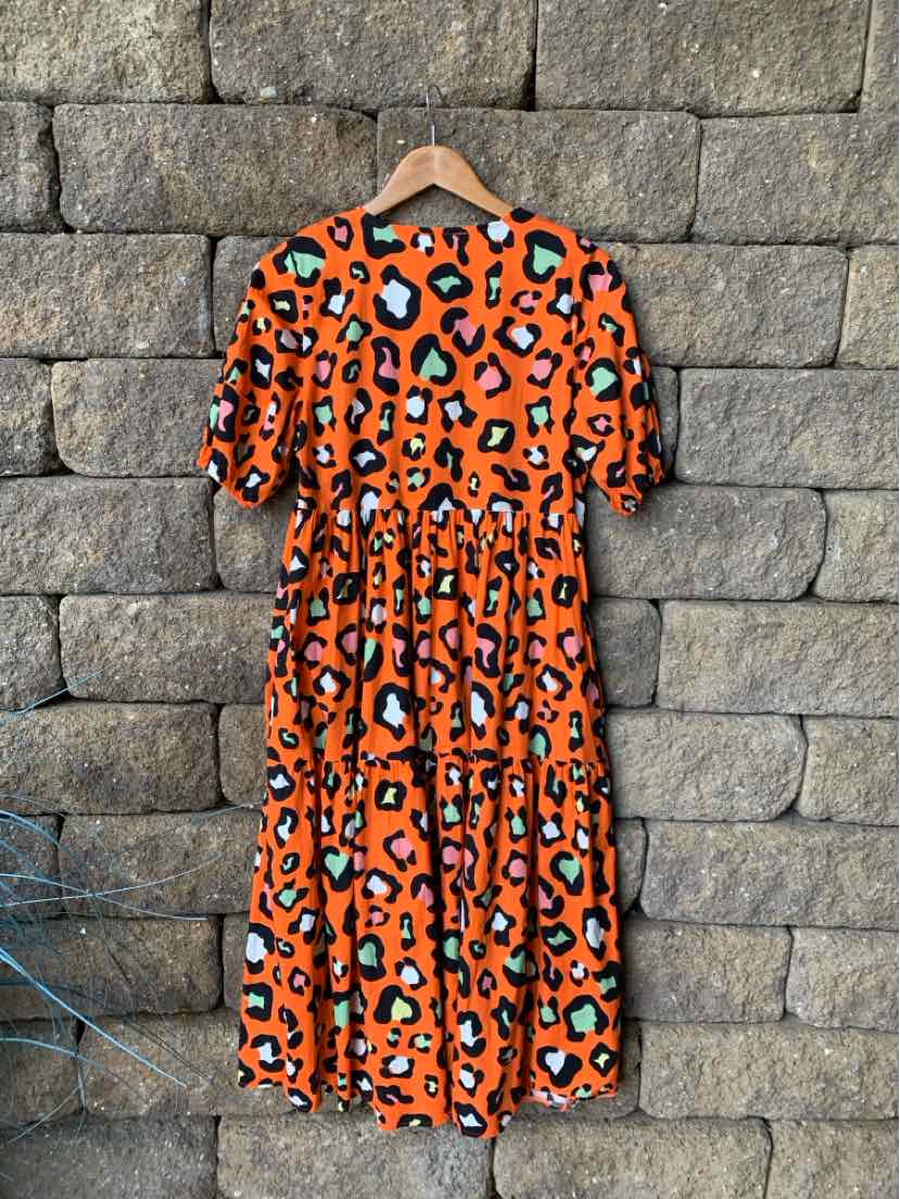 Orange midi dress with black and white leopard print, tiered skirt, and short sleeves.
