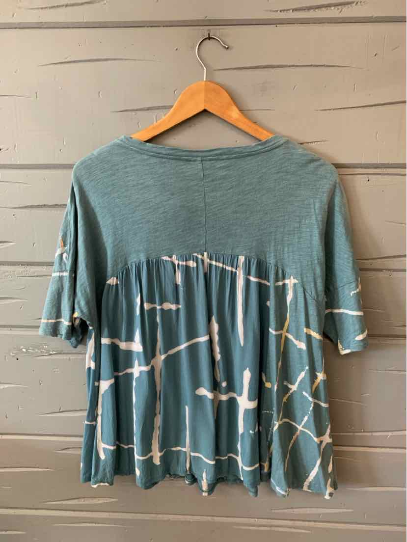 Short-sleeve teal top with loose fit and white abstract tie-dye pattern across the lower back and sleeves.