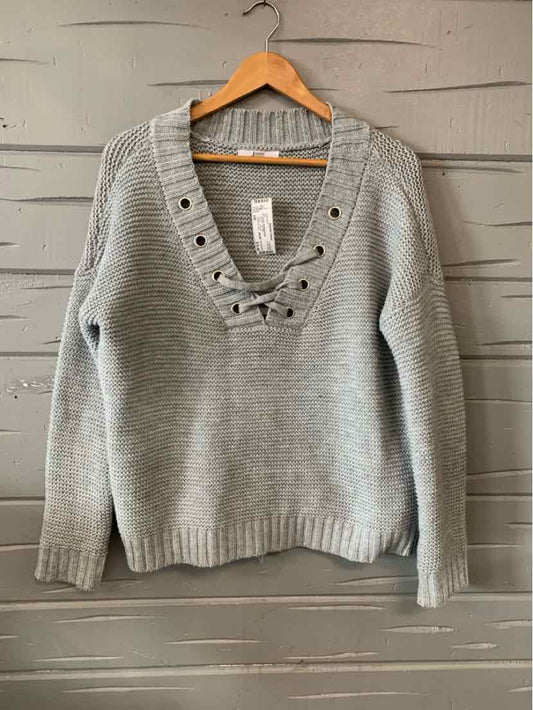 Light gray knit sweater with lace-up V-neck and ribbed cuffs and hem.