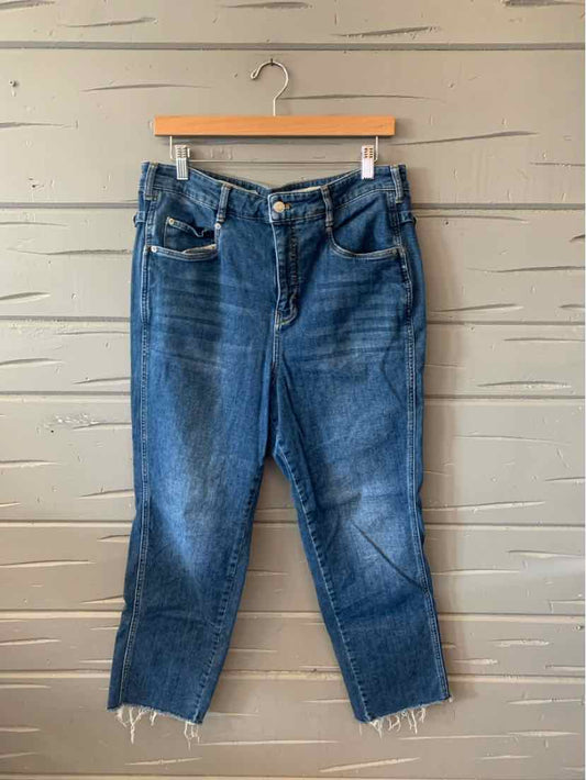 Blue denim jeans with a high waist, button fly, and raw frayed hems hanging on a wooden hanger.