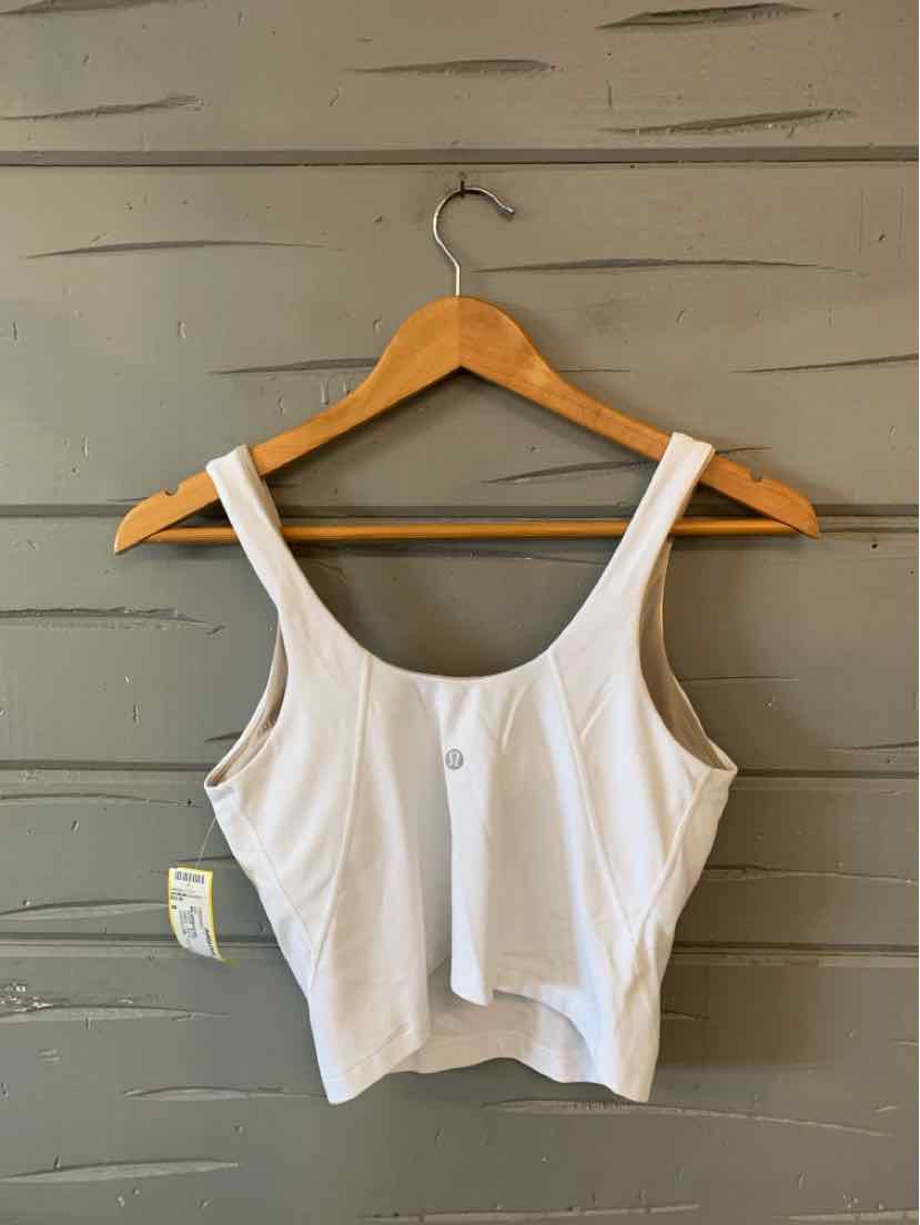 White sleeveless crop top with wide straps and fitted silhouette on wooden hanger.