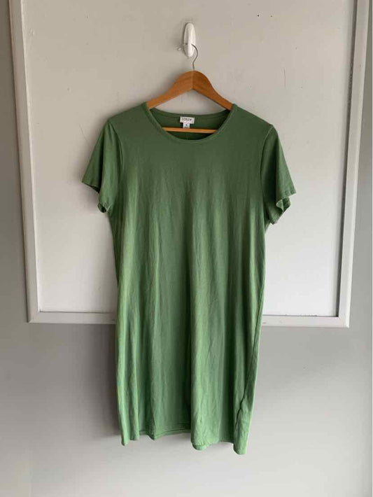 Short green crew neck dress with short sleeves and a relaxed fit hanging on wooden hanger.