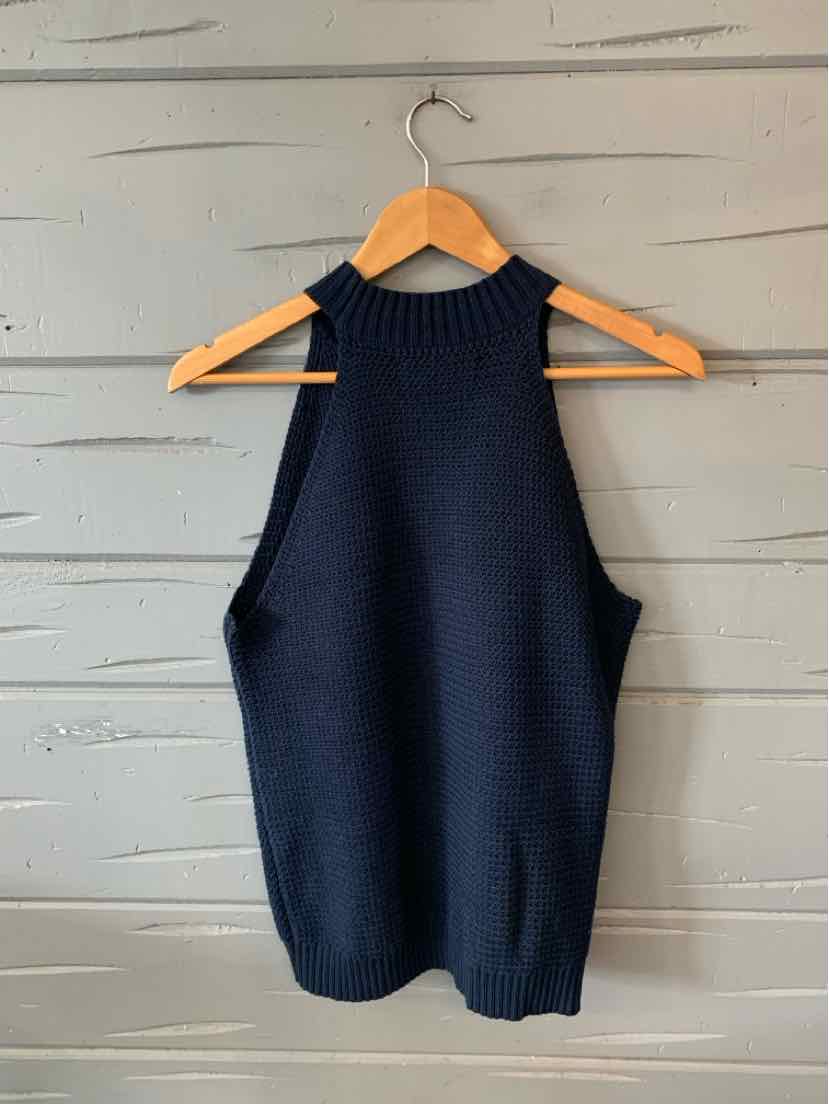 Navy blue sleeveless knit sweater with high ribbed neckline and relaxed fit hanging on wooden hanger.