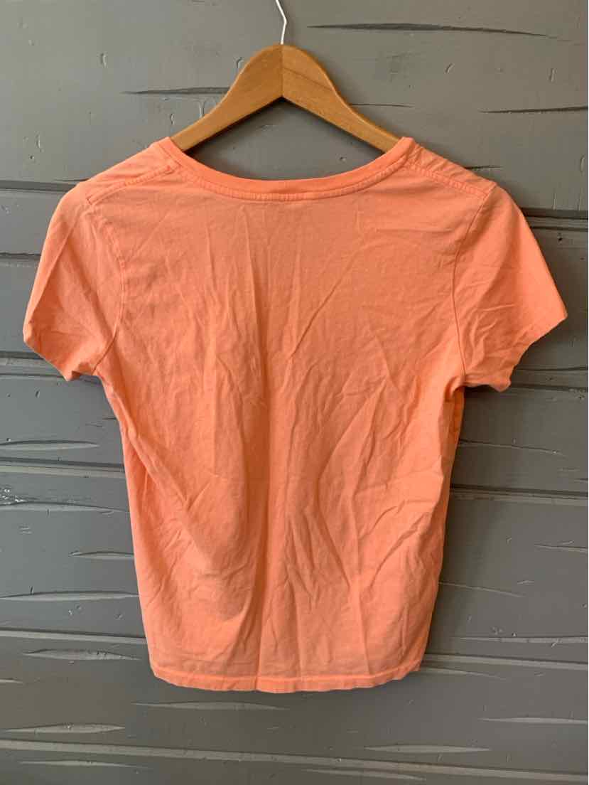 Light orange short-sleeve polo shirt with solid color, hanging on wooden hanger.