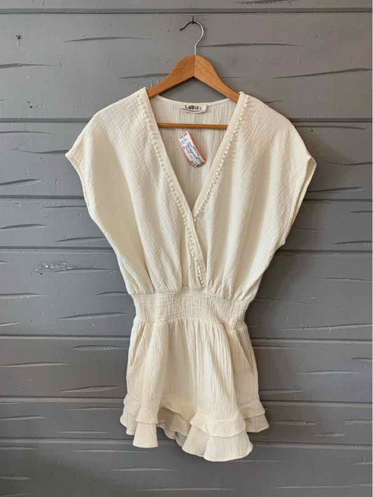 Cream short-sleeve romper with deep V-neck, elastic waist, and ruffled hem.