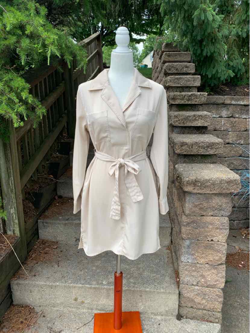 Light beige knee-length shirt dress with long sleeves, button front, collar, and waist tie belt.
