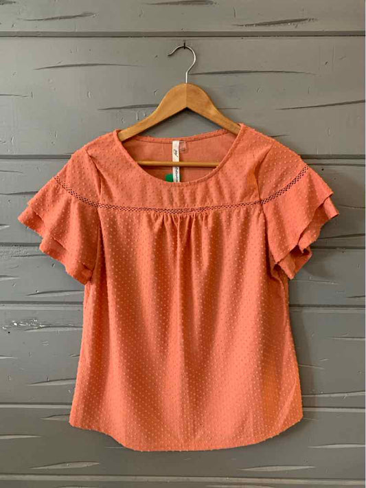 Coral orange textured short-sleeve blouse with ruffle sleeves and round neckline on wooden hanger.