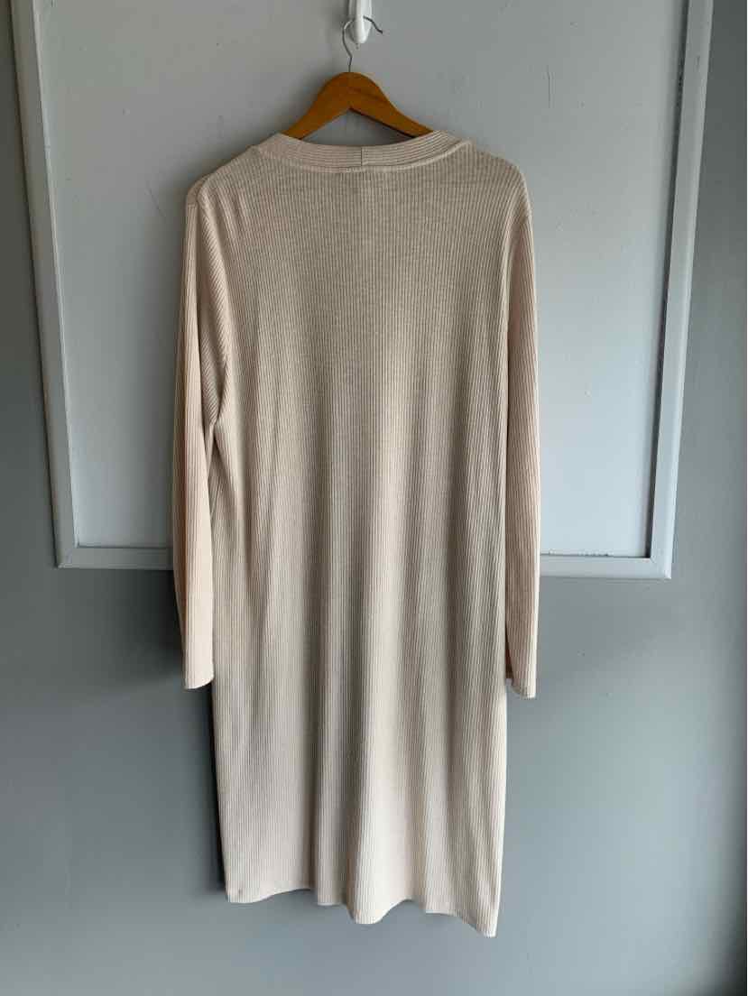 Long beige knit sweater dress with long sleeves and crew neckline hanging on wooden hanger.