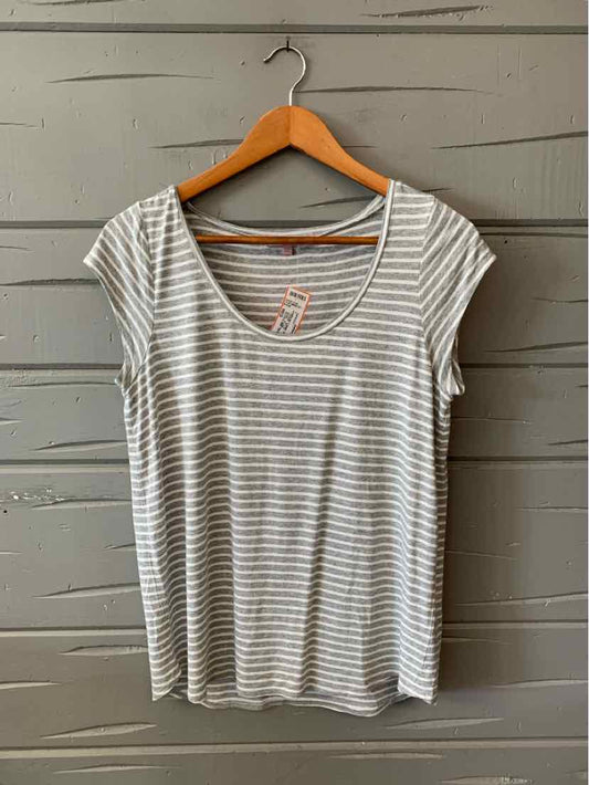 Light gray and white striped short-sleeve scoop neck t-shirt hanging on wooden hanger against gray wooden wall.