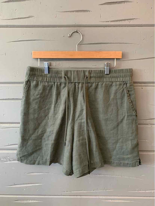 Olive green casual shorts with elastic waistband and side pockets hanging on wooden hanger.