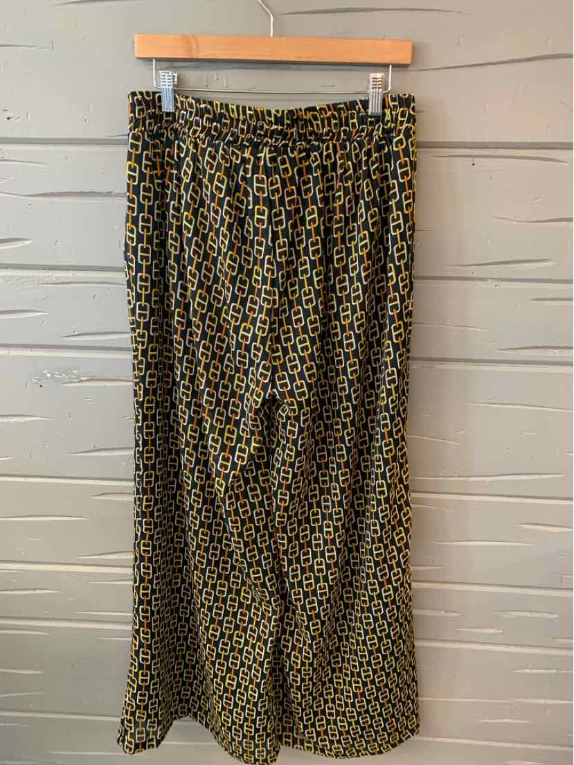 Black and gold patterned wide-leg pants with elastic waistband hanging on wooden hanger.