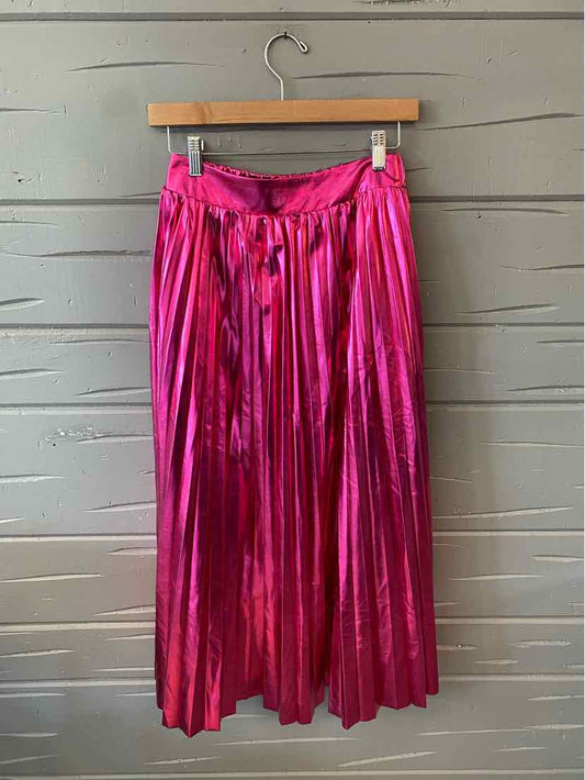 Bright pink metallic pleated midi skirt with elastic waistband hanging on wooden hanger.