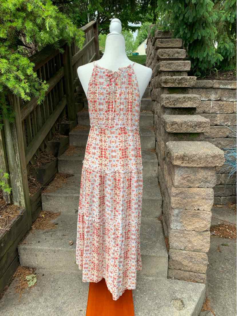 Sleeveless pink floral midi dress with tiered skirt and high neckline on mannequin outdoors.