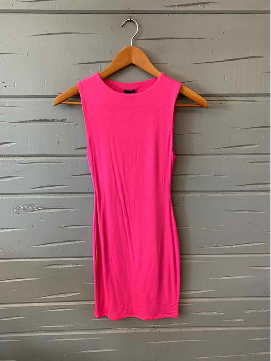 Sleeveless solid bright pink bodycon dress hanging on wooden hanger against gray textured wall.