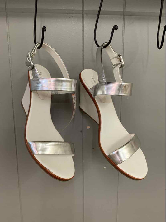 White open-toe sandal with shiny silver ankle and toe straps, flat sole, and adjustable buckle.