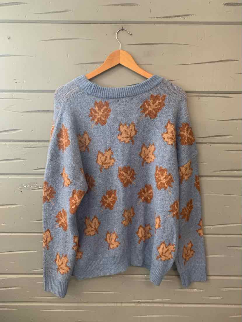 Light blue knit sweater with orange-brown leaf patterns scattered all over, long sleeves, crew neckline.