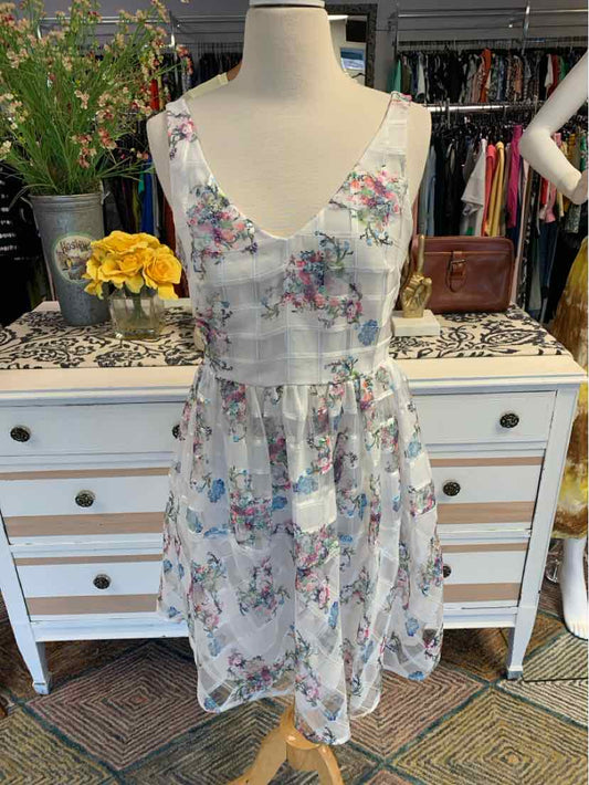Sleeveless floral midi dress in white with pink, purple, and green flowers and a fitted waist.
