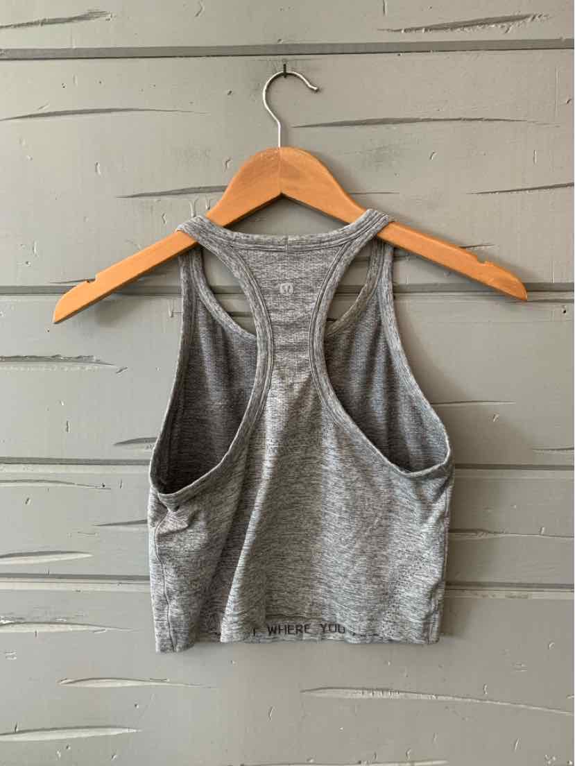 Gray sleeveless athletic crop top with racerback design, made from soft, stretchy fabric.
