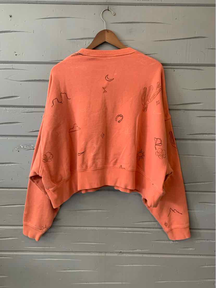 Coral orange cropped sweatshirt with loose fit and abstract black doodle designs on back and sleeves.