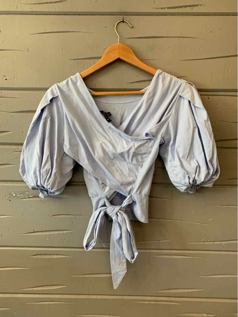 Light blue wrap blouse with puffed elbow-length sleeves and front tie detail.