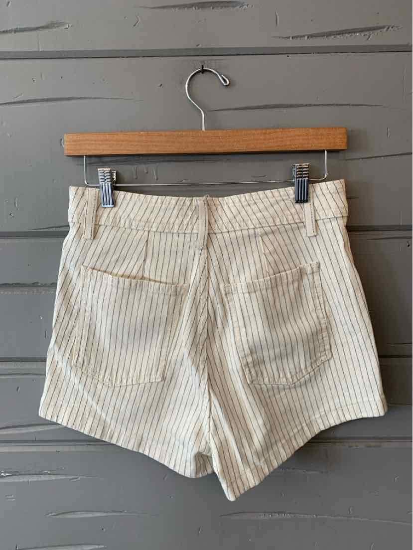 White high-waisted shorts with thin vertical beige stripes and back welt pockets on a wooden hanger.