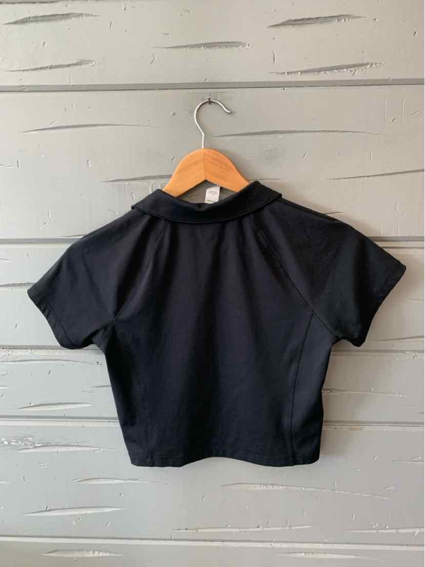 Black short-sleeve cropped workout top with a high collar and fitted silhouette hanging on wooden hanger.