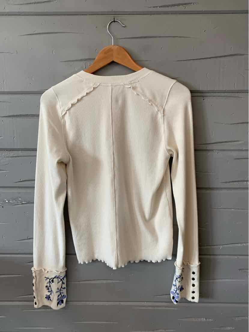 Cream long-sleeve cardigan with scalloped edges and floral embroidery on wide cuffs.