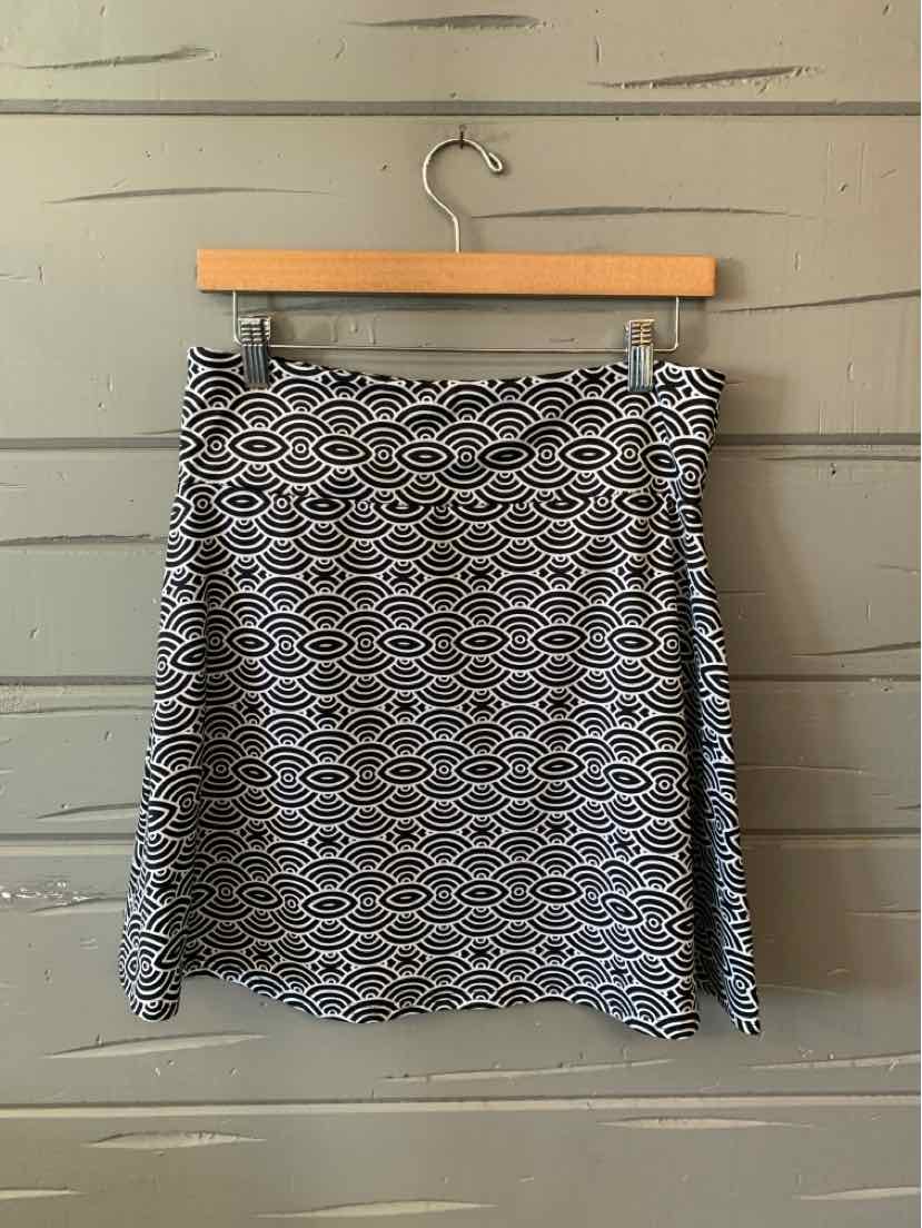 Black and white patterned knee-length skirt with abstract geometric design on a wooden hanger.