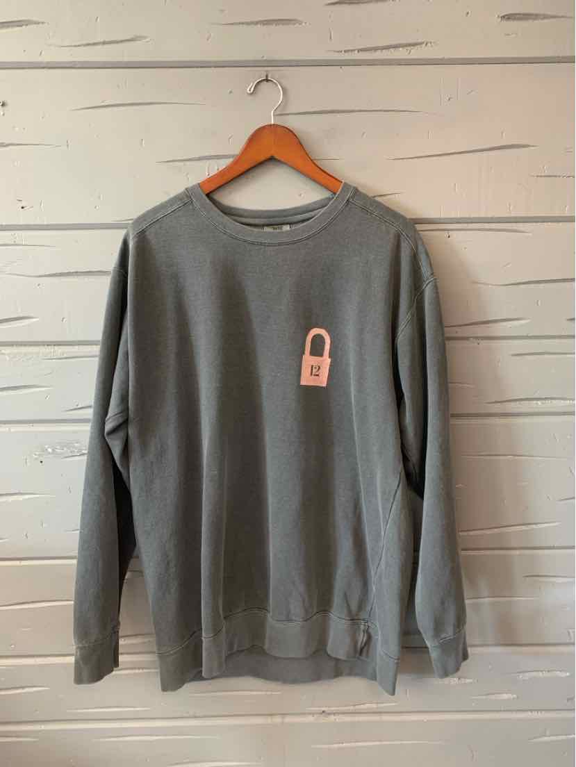 Gray long-sleeve crewneck sweatshirt with small pink lock graphic on chest, relaxed fit, hanging on wooden hanger.