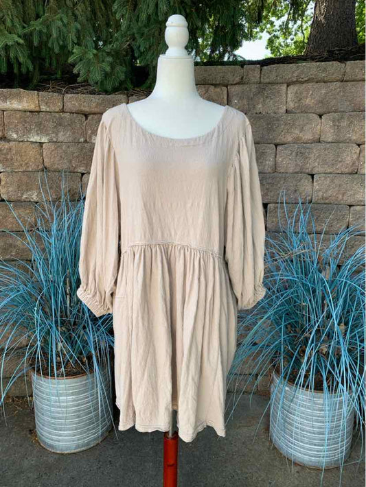 Beige long-sleeve loose dress with gathered waist and round neckline displayed on mannequin.