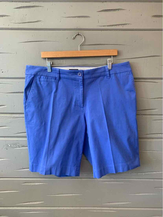 Light blue tailored knee-length shorts with belt loops and front pockets hanging on wooden hanger.