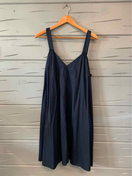 Navy blue sleeveless dress with wide straps and a loose, flowing fit hanging on wooden hanger.