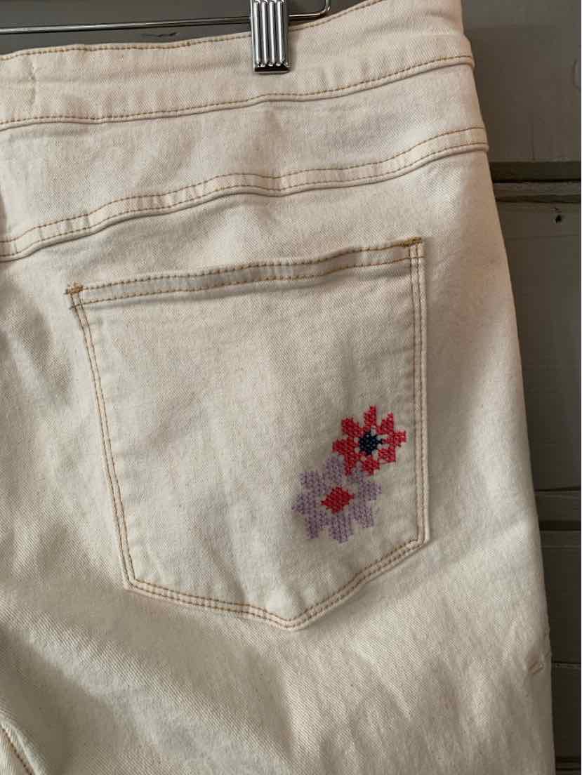 Off-white denim jeans with back pocket featuring small red and purple floral embroidery.