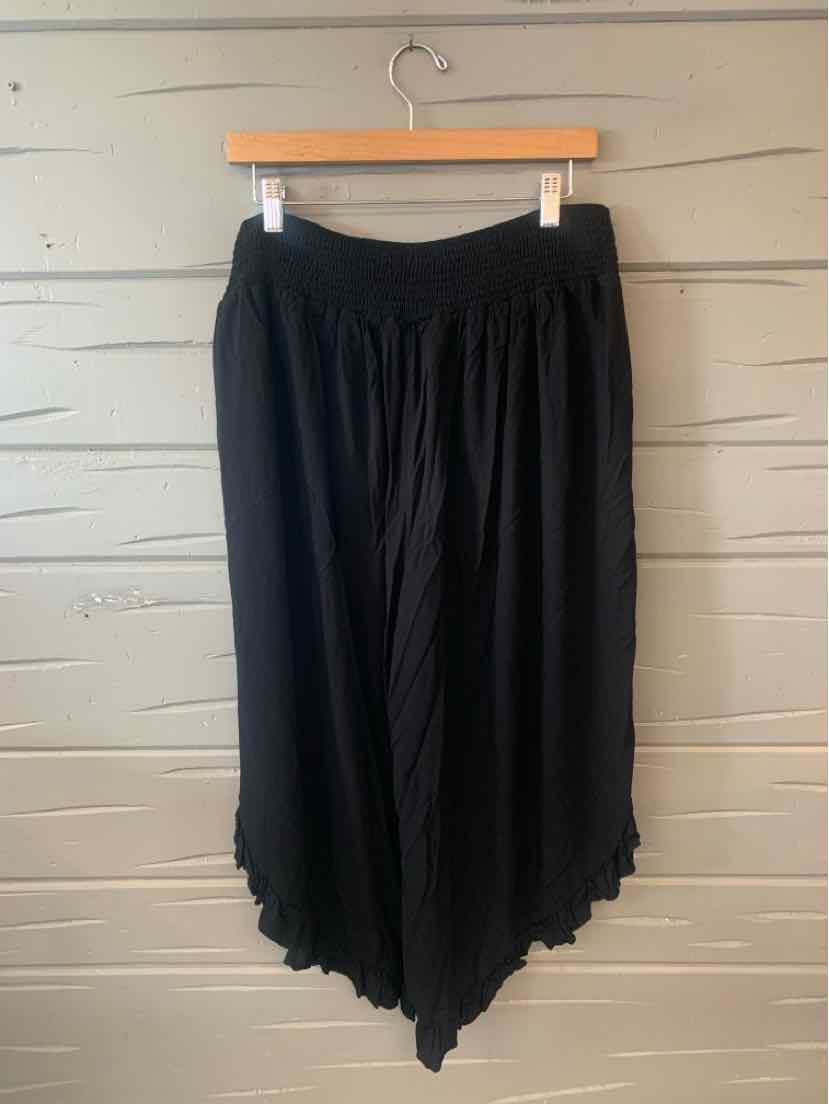 Black flowy wide-leg pants with an elastic waistband and asymmetrical hem.