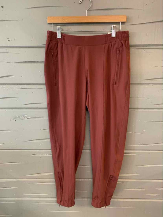 Brown high-waist leggings with a solid design and elastic waistband hanging on a wooden hanger.