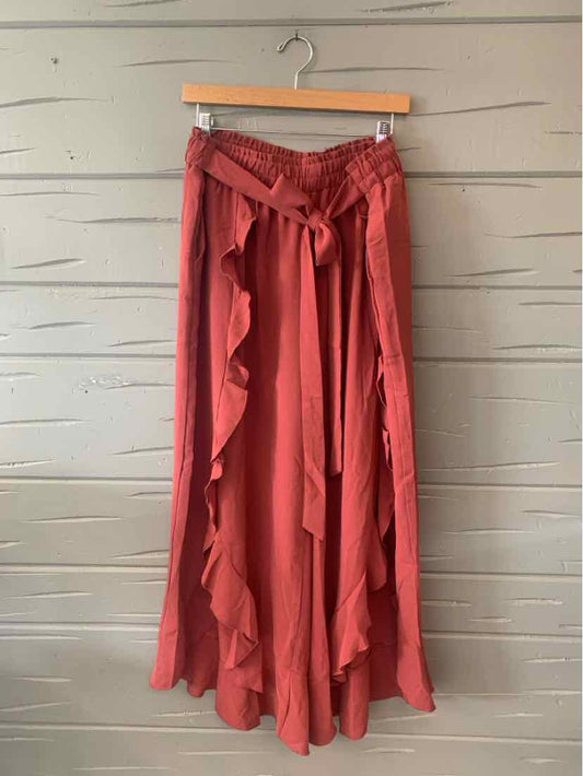 Mauve wrap skirt with ruffled edges and a matching fabric belt hanging on wooden hanger.