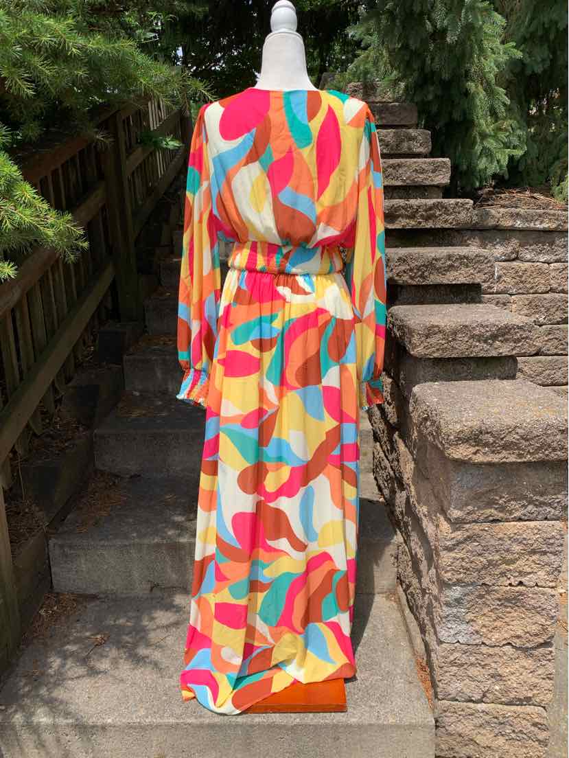 Colorful long-sleeve maxi dress with abstract red, pink, orange, blue, and beige patterns and a cinched waist.