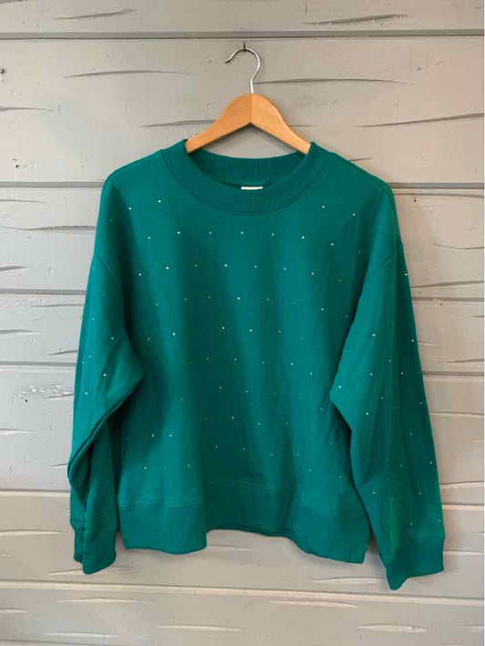 Teal green oversized sweatshirt with scattered rhinestone accents and long sleeves on wooden hanger.