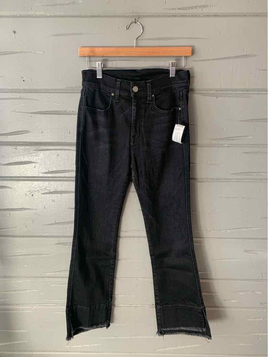 Black denim jeans with high waist, raw hem, and frayed side slits, size 6 hanging on wooden hanger.