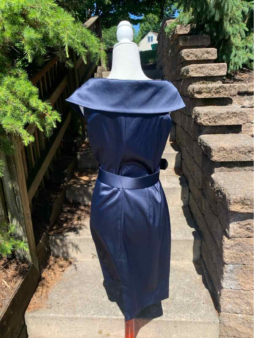 Navy blue sleeveless dress with wide off-shoulder collar and fitted waist detail on mannequin outdoors.