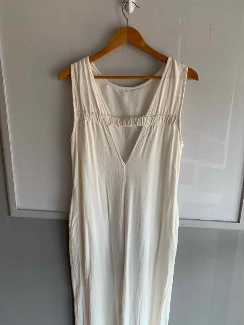 White sleeveless dress with wide straps, gathered detail at bust, and flowy fabric hanging on wooden hanger.