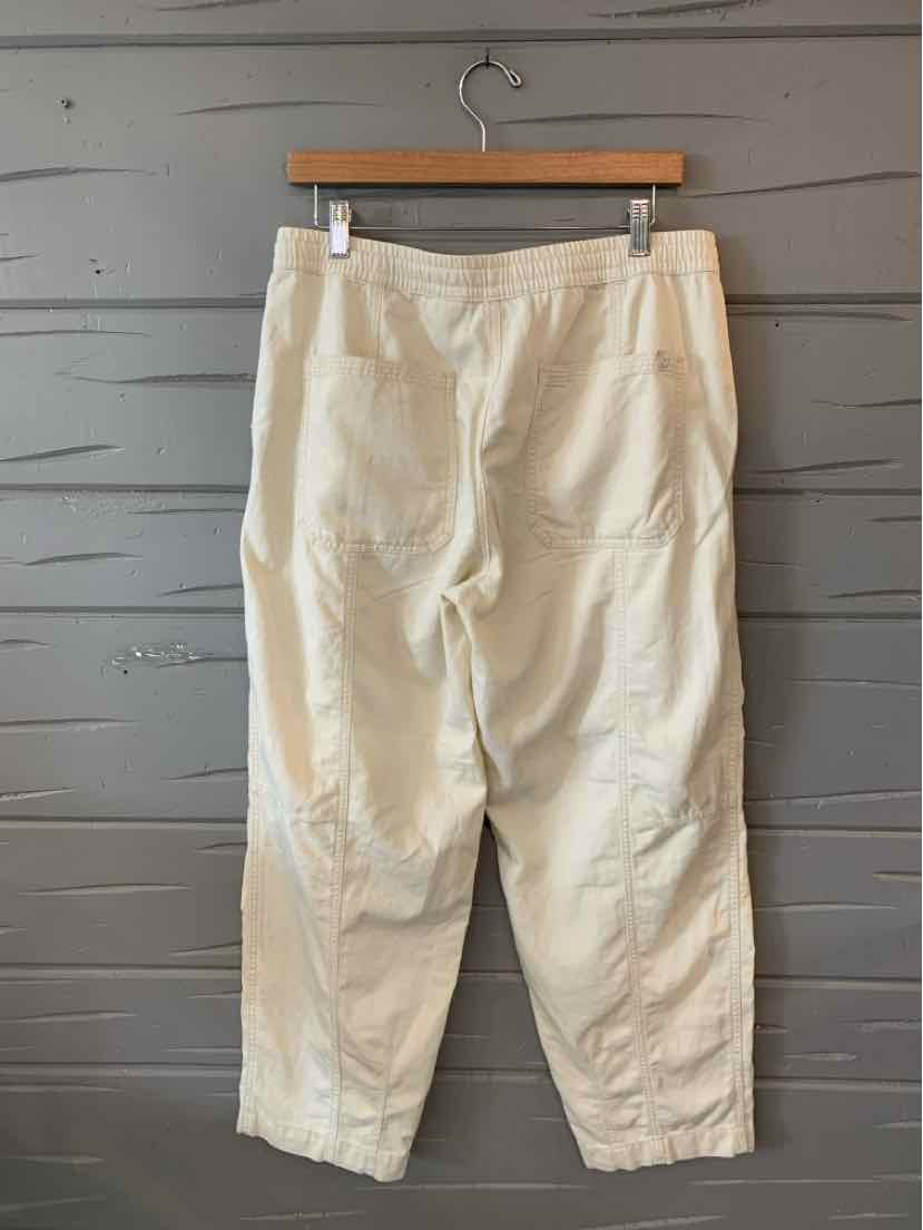 Off-white casual pants with a relaxed fit, elastic waistband, and side pockets, hanging on a wooden hanger.